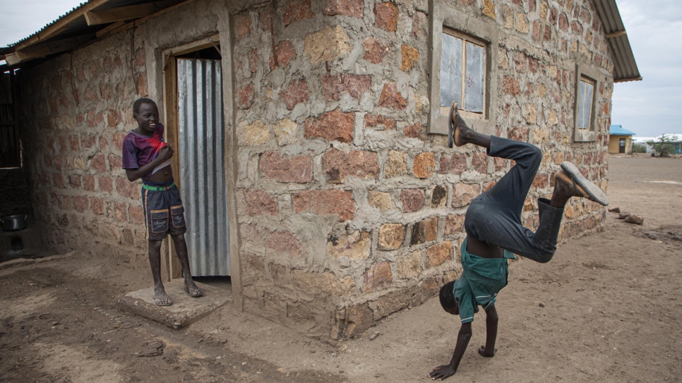 South Sudanese refugee Luiz Ohisa, 12, plays outside his newly-constructed home n Kalobeyei settlement, Kenya, as his brother looks on.