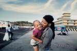 Nigerian refugee Shalom, 24, hugs her young daughter after being rescued at sea and taken to the Italian port of Augusta. 