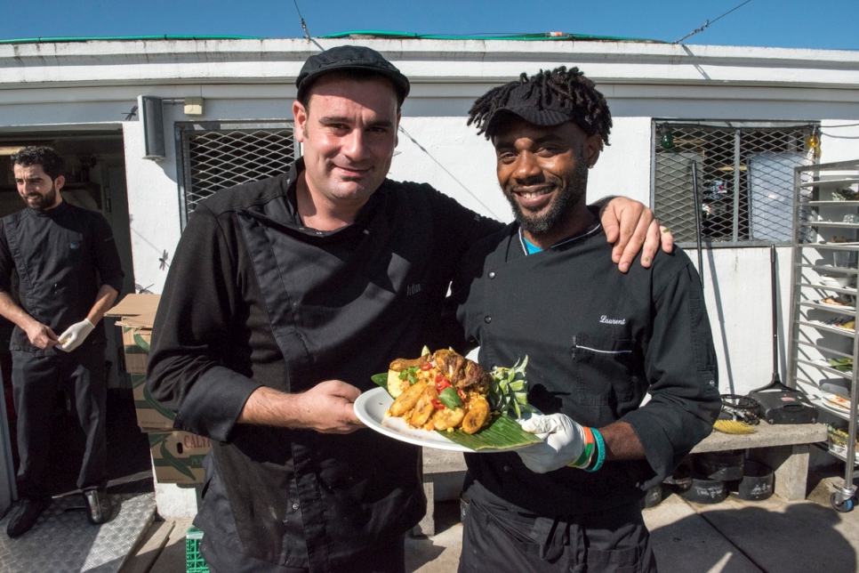 Eze (à droite) présente son riz jollof à la banane plantain, à côté d'Ardian, le chef résident.