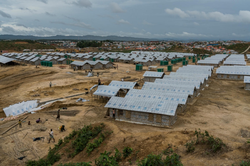 عمال يضعون اللمسات الأخيرة على بناء ملاجئ جديدة للعائلات التي نقلت من المنازل الأكثر عرضة لخطر الانهيارات الأرضية والفيضانات في مخيم كوتابالونغ للاجئين، بالقرب من كوكس بازار، بنغلاديش.