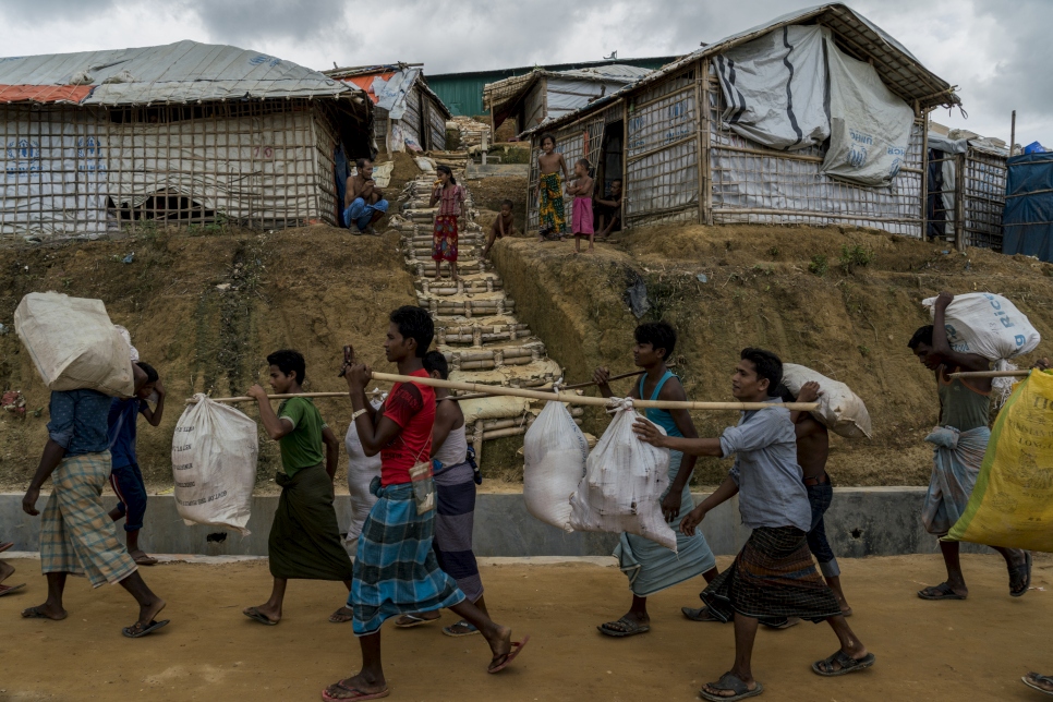 لاجئون من الروهينغا كانوا يعيشون في خيام معرضة لخطر الانهيارات الأرضية، يحملون أمتعتهم خلال نقلهم إلى القسم 4 الجديد الملحق بمخيم كوتابالونغ للاجئين في بنغلاديش.