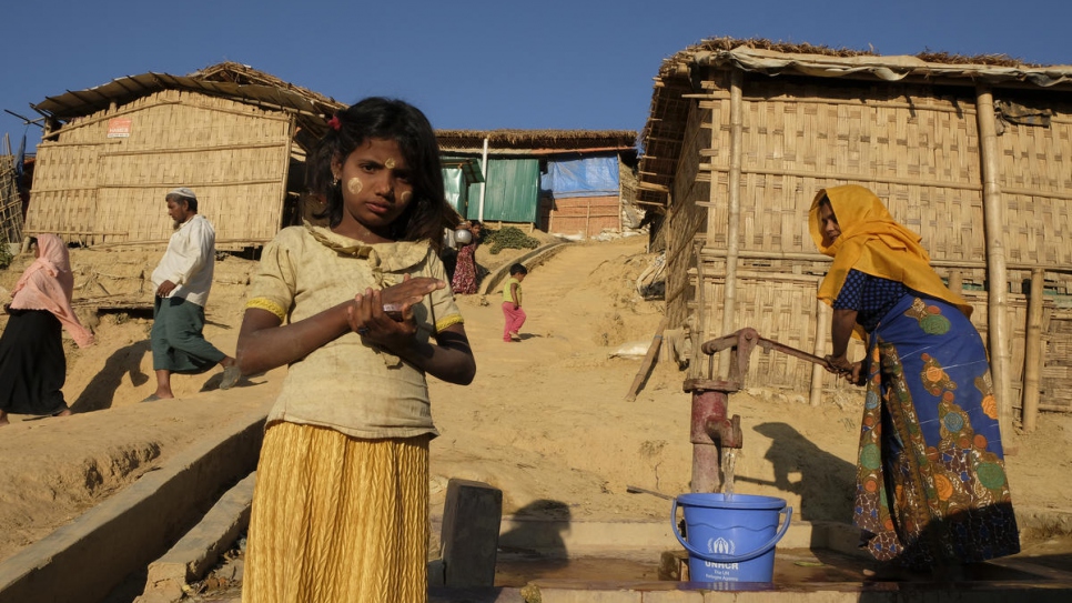 As camp life goes on behind her, Minara, a young Rohingya from Myanmar, pauses in the late afternoon sunlight at Kutupalong refugee camp in Bangladesh.