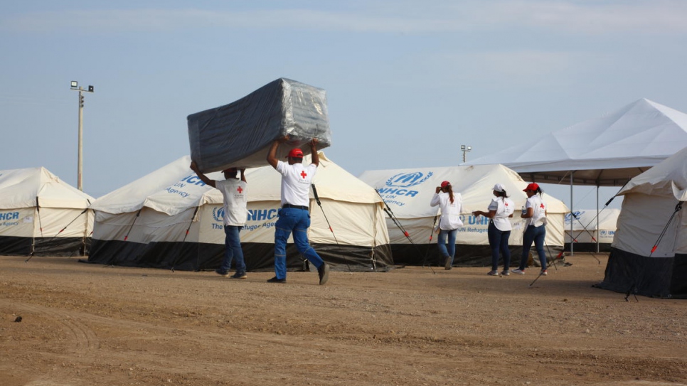 Des bénévoles des ONG et des institutions locales transportent des matelas dans le nouveau centre de réception de Maicao, Colombie. 