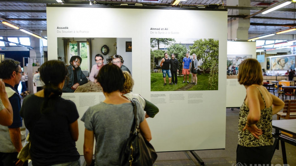 Des visiteurs regardent des portraits de l'exposition 'No Stranger Place' à Ground Control à Paris le 20 juin. Cette série de portraits, développée avec l'auteure Clémentine Baron en France, capture les liens d'amitié tissés entre des invités réfugiés et des hôtes européens à travers le continent. En partenariat avec le HCR, l'organisation a permis d'identifier les familles.