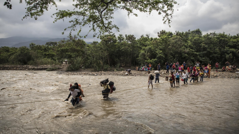 Venezuelan refugees and migrants use a rope to guide themselves across the rain-swollen Tachira River to reach Cúcuta, Colombia.