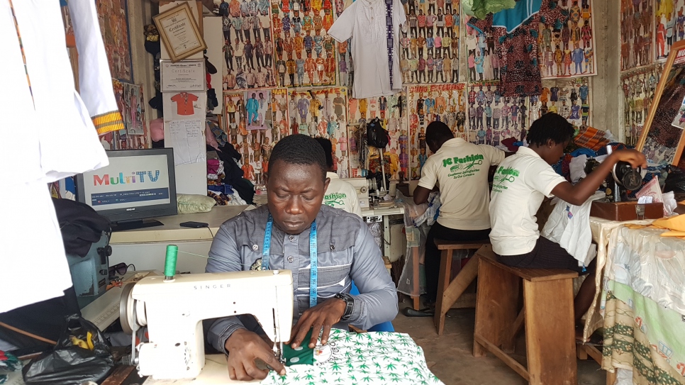 Ivorian refugee and fashion designer Bouhe Jean Claude works at his sewing machine in his tailoring shop in central Ghana.