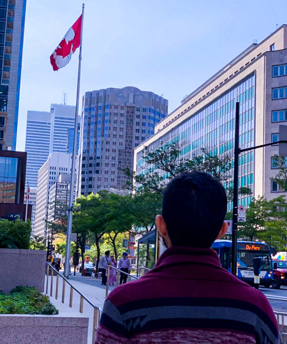 a young Yemeni man looks up at the Canadian flag