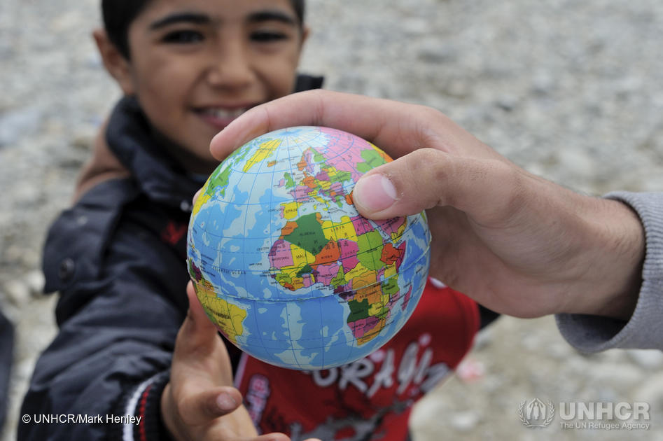 Young child, possibly a student, holds a globe 