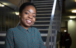 a young woman stands at the bottom of staircase