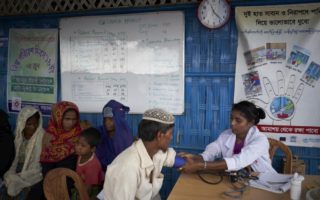 Refugee man gets his blood pressure checked by a nurse