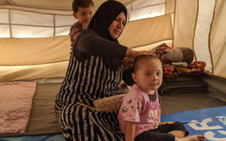 A Syrian refugees sits with her family as they prepare for winter