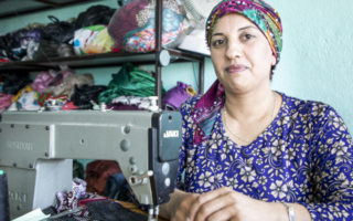 A seamstress from Syria sits at a sewing machine