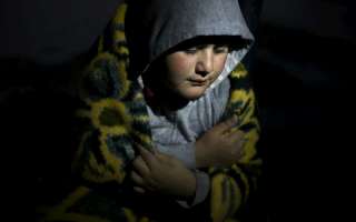 A displaced young Iraq boy in the north of the country uses a blanket to protect himself from the cold as a storm rages outside the half-built structure where he and his family have found shelter in Iraq's Kurdistan region.