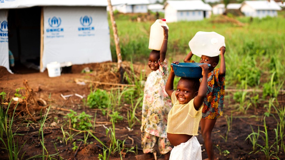 Three of Jean’s children carry water to their new home in Bili refugee camp, DRC. 