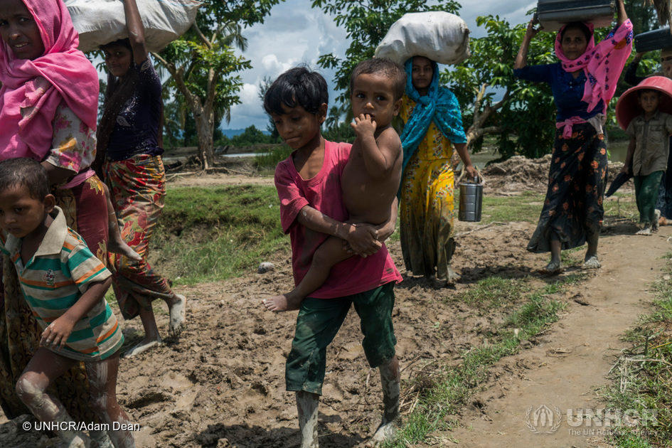 En Rohingya-dreng bærer sin lillebror under flugten med sin familie til Whaikhyang, Bangladesh. © UNHCR/Adam Dean