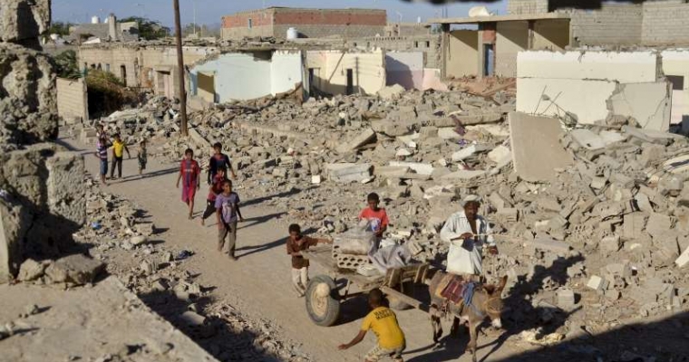 Children play as a donkey cart passes destroyed buildings in the Al-Ora's neighbourhood of Zinjibar.