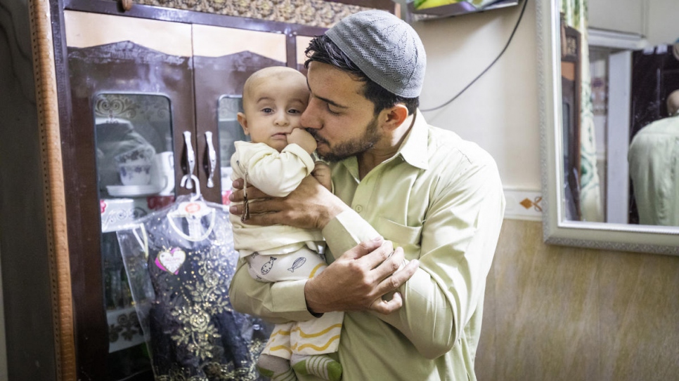 Shifat cradles his son in the small apartment where he lives with his family. 