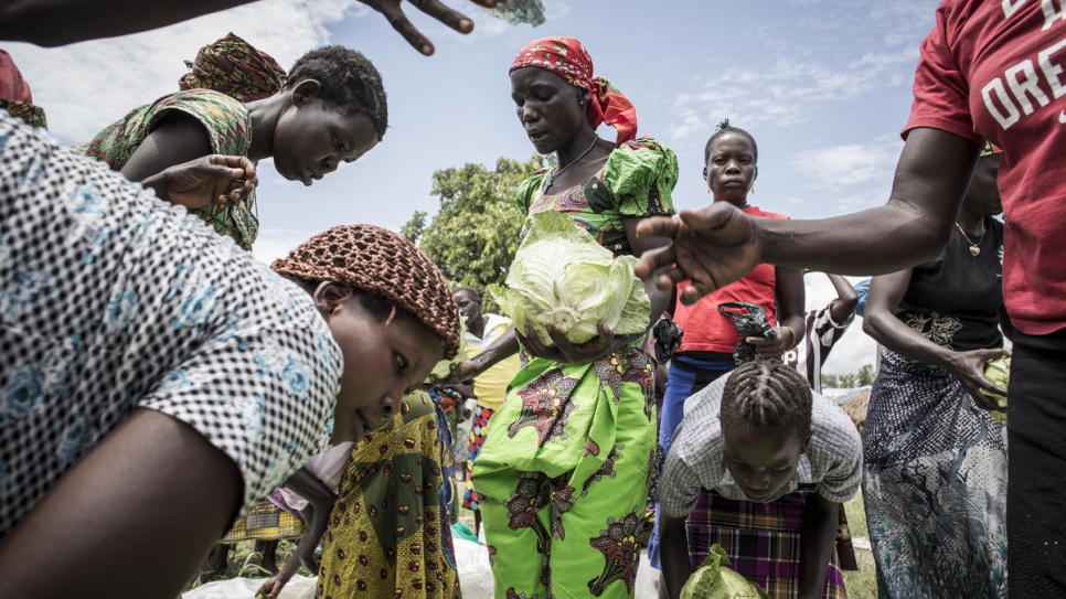 Neema (centre) sells cabbages on market day, grown on land she works with a farming cooperative comprising both host and refugee farmers.