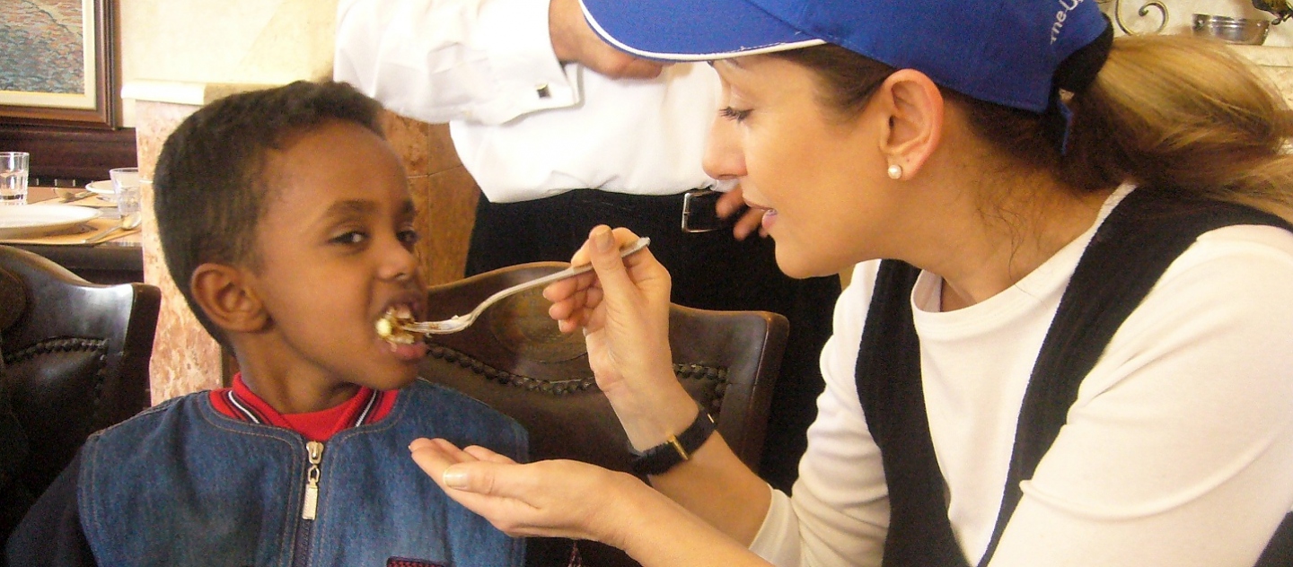 Goodwill Ambassador Muazzez Ersoy feeds a young boy at a lunch she hosted for refugee families in the Turkish capital, Ankara.