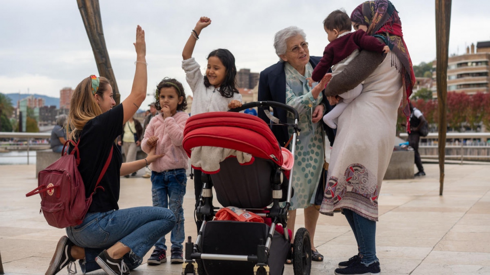 Volunteers Karmele Villarroel Labanda (kneeling) and Begoña Herrero entertain the family on a day trip to the Guggenheim Museum in Bilbao.