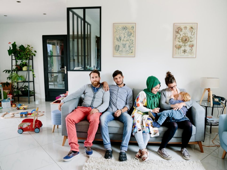 France. Anaïs, Vincent, and their son César, host Afghan refugees Zulfeqar and Battarine, in Saint-Priest. This portrait is part of the No Stranger Place series, which portrays locals and refugees living together