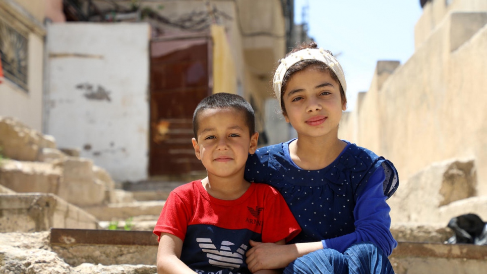Nadia, 12, and her youngest brother Abed, 5, sit in the alleyway outside their home in East Amman. They and their three other siblings have been taking turns using the family's one TV and mobile phone.