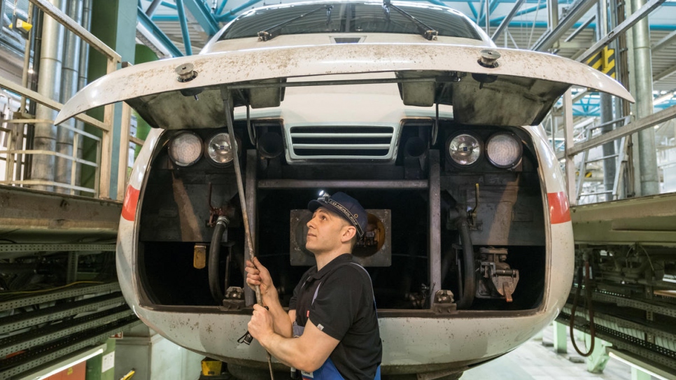 Syrian refugee Mohammad Alkhalaf checks the railcar of an Intercity Express (ICE) train at Deutsche Bahn's Hamburg-Eidelstedt depot, where he is training to be an engineer.