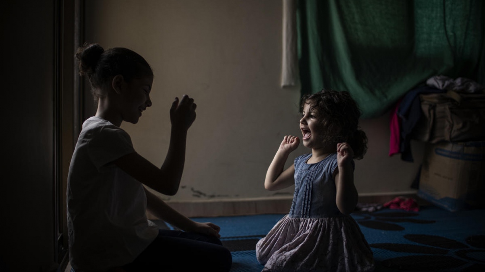 Layan, 10, plays a game with her younger sister Yasmine, 3.