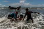 Des réfugiés rohingyas débarquent d'un bateau de pêche au milieu de l'eau, à l'approche de la plage de Dakhinpara, au Bangladesh. 