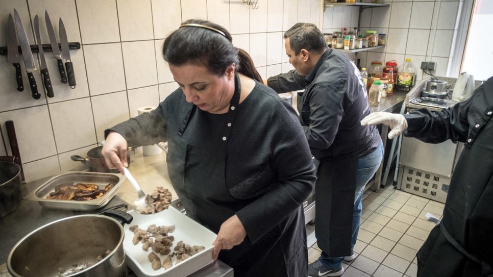 Salma Al Armarchi, une réfugiée syrienne, en train de cuisiner avec un employé dans sa 	cuisine de Berlin d'où elle exploite son entreprise, Jasmin Catering. 