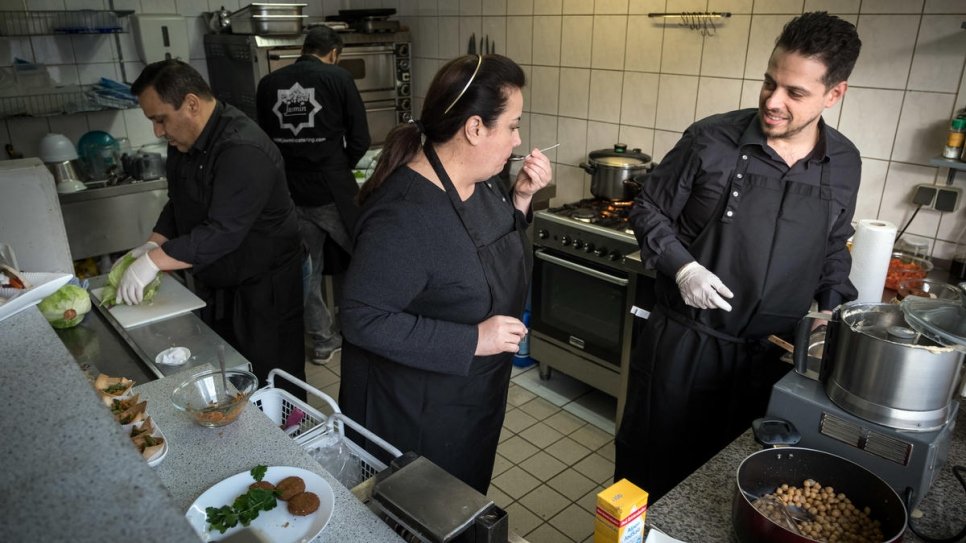 Salma Al Armarchi (au centre), une réfugiée syrienne de 53 ans, en train de cuisiner avec son fils Fadi Zaïm (à droite), 32 ans, et deux autres employés dans la cuisine de Berlin d'où elle exploite son entreprise, Jasmin Catering. 
