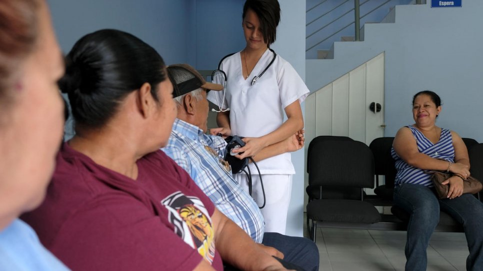 Une infirmière prend la tension d'un patient au Centre de soutien global de la Sainte Trinité, administré avec l'appui du HCR à Chamalecón, un quartier de San Pedro Sula, au Honduras.