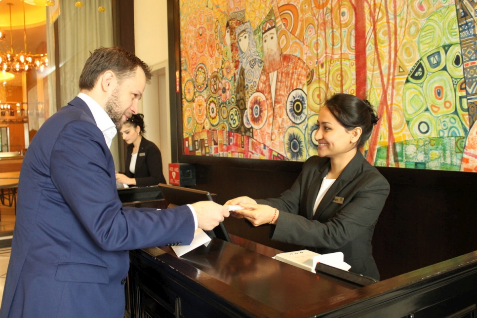 Tajikistan. Afghan refugee Nargis, confidently receiving a guest at the Front Desk, during the Apprenticeship Programme at the renown Sheraton Hotel in Dushanbe