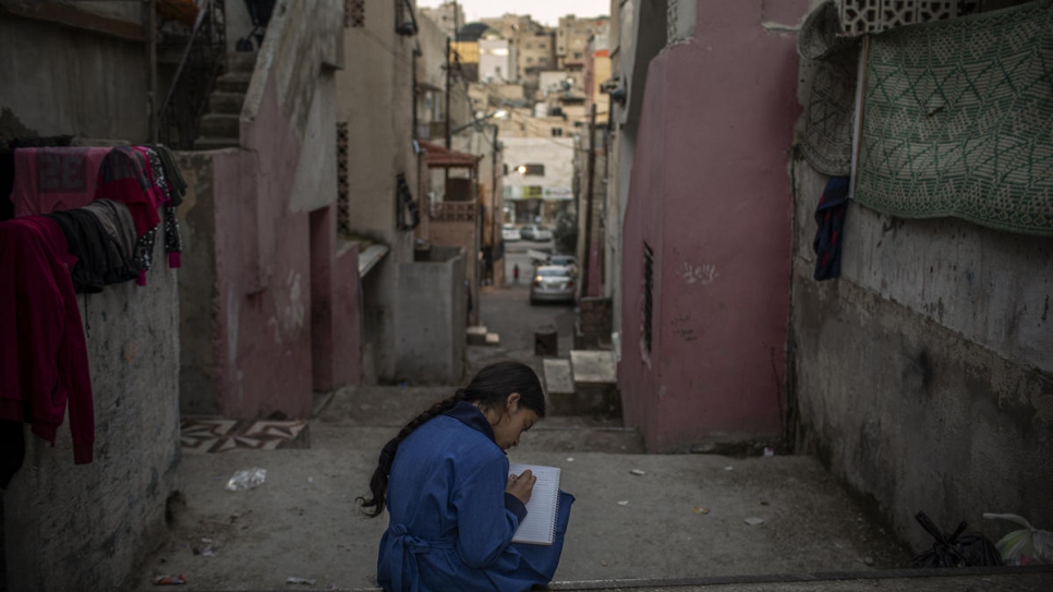 Namaat, onze ans, écrit un poème sur les marches devant sa maison. 