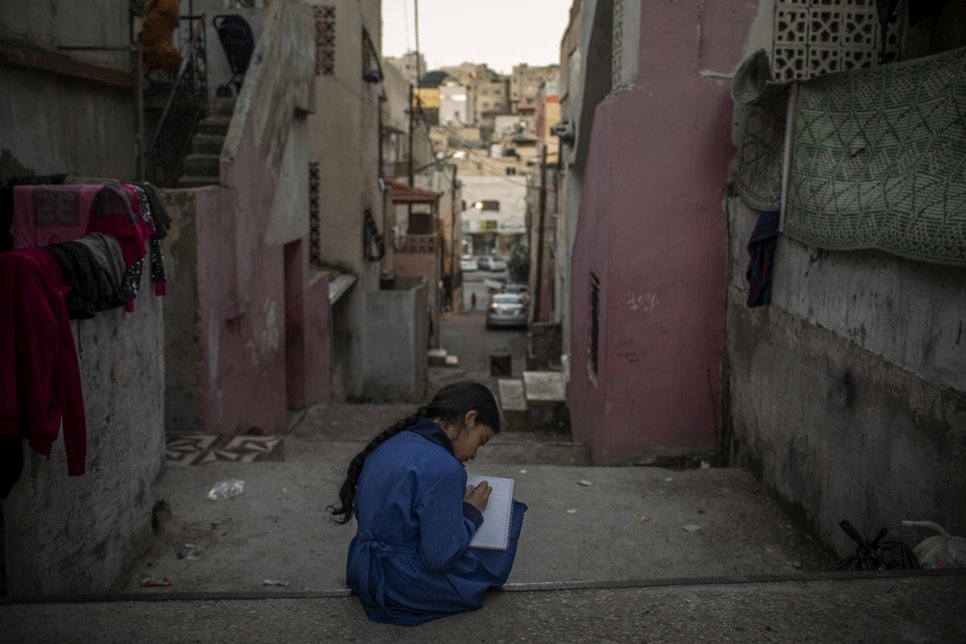 Naamat, de 11 años, escribe un poema en las escaleras afuera de su hogar.