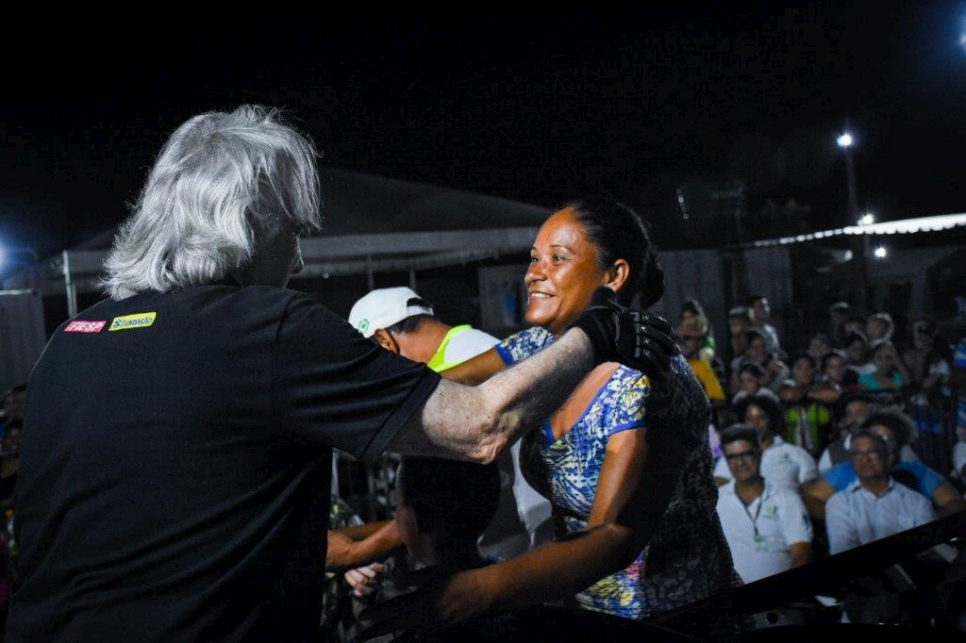 Guillermo, Katty y el pequeño Arnel actuando en el escenario junto al director de orquesta brasileño João Carlos Martins, mientras la población del albergue canta con ellos.