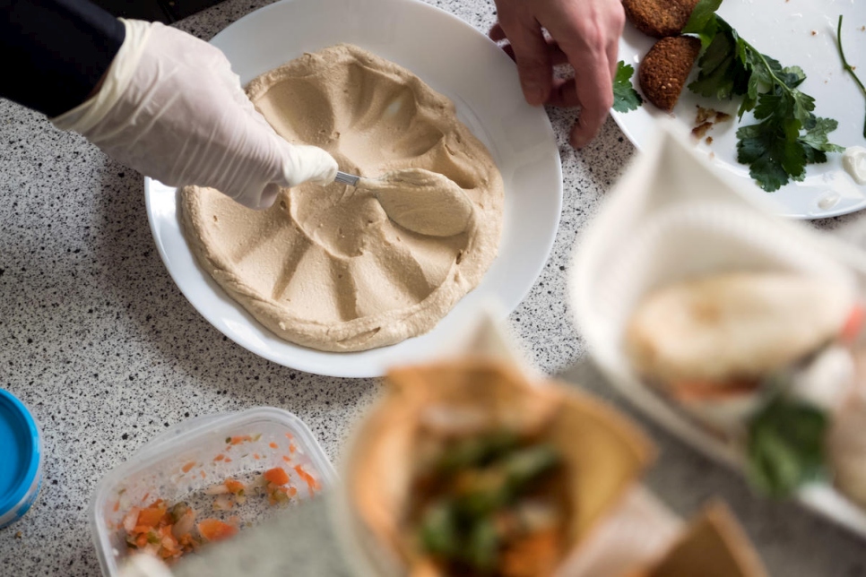 El refugiado sirio Fadi Zaim, de 32 años, prepara un plato de hummus en la cocina de su madre Salma Al Armarchi en Berlín, desde donde dirige su compañía, Jasmin Catering. 