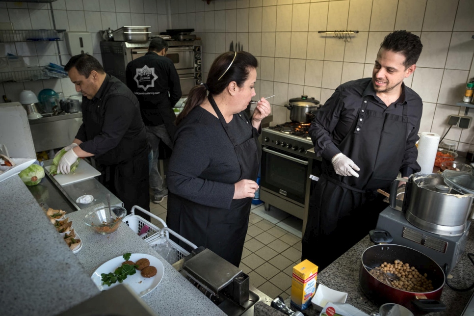 La refugiada siria Salma Al Armarchi (centro), de 53 años, cocina con su hijo Fadi Zaim (derecha), de 32 años, y dos empleados en la cocina de Berlín, donde dirige su empresa, Jasmin Catering.