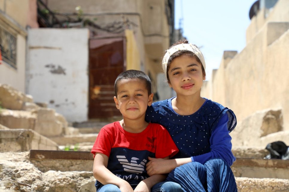 Nadia, de 12 años, y su hermano menor, Abed, de 5, se sientan en el callejón frente a su casa en Amán. Ellos y sus otros tres hermanos se han turnado para usar el único televisor y teléfono móvil de la familia. 