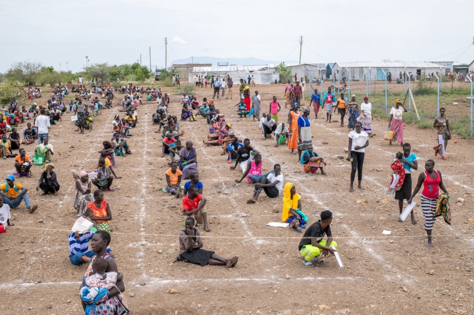 Dans l'installation de Kalobeyei au Kenya, les réfugiés pratiquent la distanciation physique en attendant une distribution de savon, de jerrycans et de bois de chauffage.  