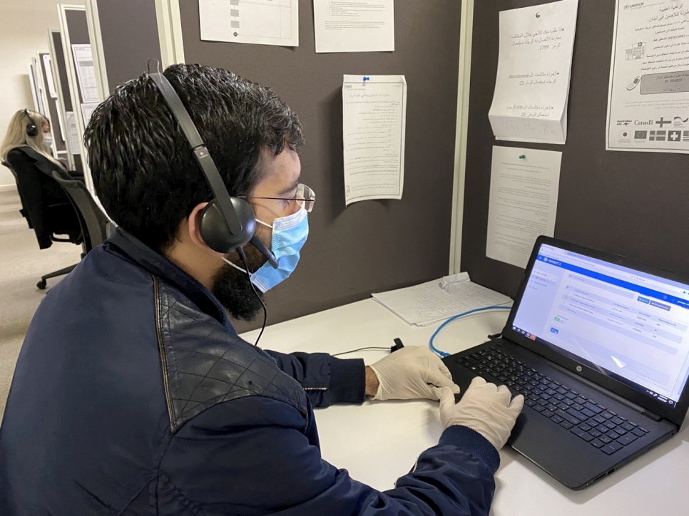 Un opérateur portant un masque de protection répond aux questions des réfugiés par téléphone au centre d'appel du HCR et du Programme alimentaire mondial à Beyrouth, au Liban. 