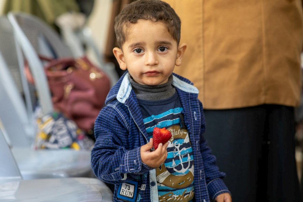 Mohammad, un réfugié syrien âgé de quatre ans, mange une fraise, alors que sa mère participe à un cours de cuisine au centre communautaire de Nuzha, soutenu par le HCR, dans l'est d'Amman, en Jordanie. 