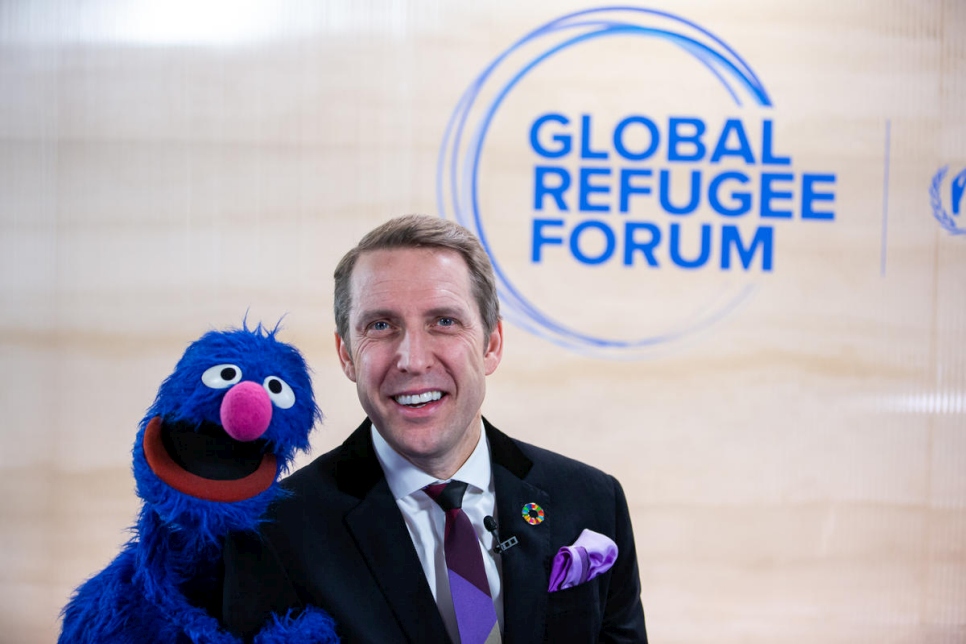 John Goodwin, CEO of the LEGO Foundation, shares a joke with the Sesame Street muppet Grover. Grover has been conducting interviews at the Global Refugee Forum to be broadcast during the "Sesame Street News" segment of the children's television programme.
