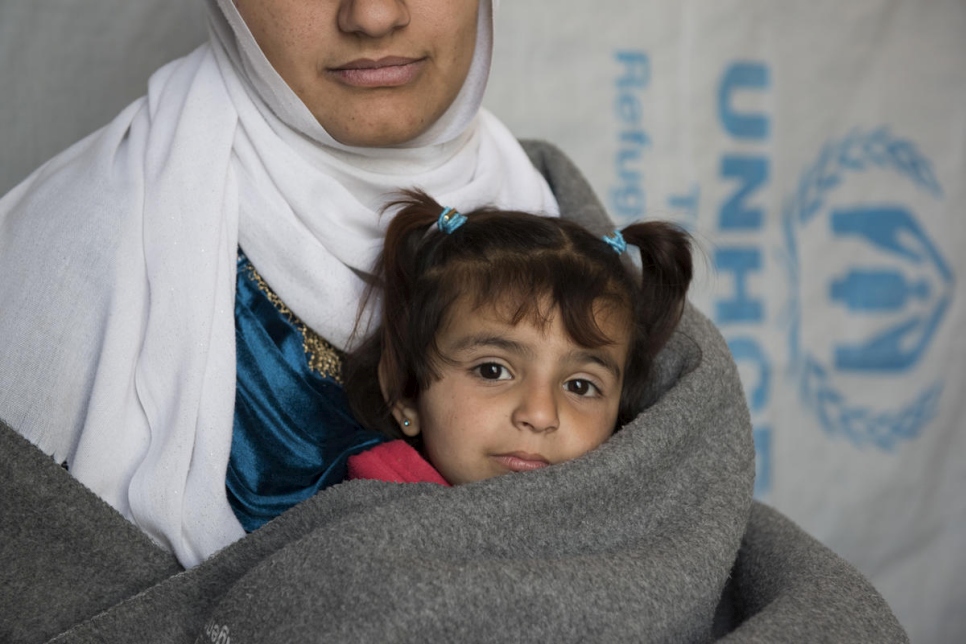 La refugiada siria Amira y su hija Amani fotografiadas en su casa, situada en un asentamiento informal en el valle de Bekaa, en el Líbano, en febrero de 2018. La familia construyó su refugio con madera y una lona suministrada por ACNUR.
