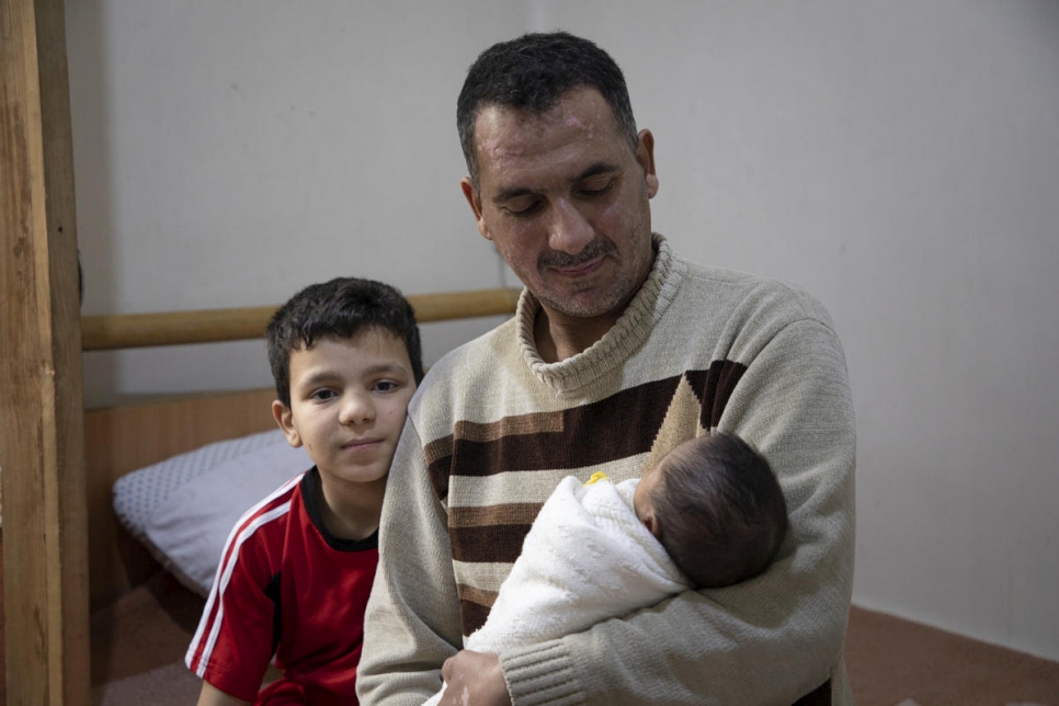 يحمل ربيع، وهو نازح سابق، طفله الرضيع مصطفى، في منزلهما في حلب، سوريا.