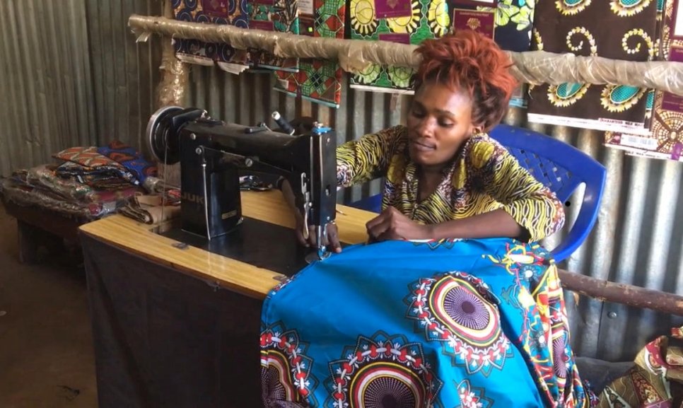 هوتا تحيك فستاناً في متجرها في مخيم كاكوما في كينيا، حيث توظف سبعة لاجئين آخرين.