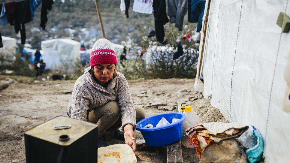 Fahima, who fled Afghanistan with her husband and five children, bakes flatbread in a makeshift oven outside the family's hut among the olive groves near the Moria reception and identification centre.