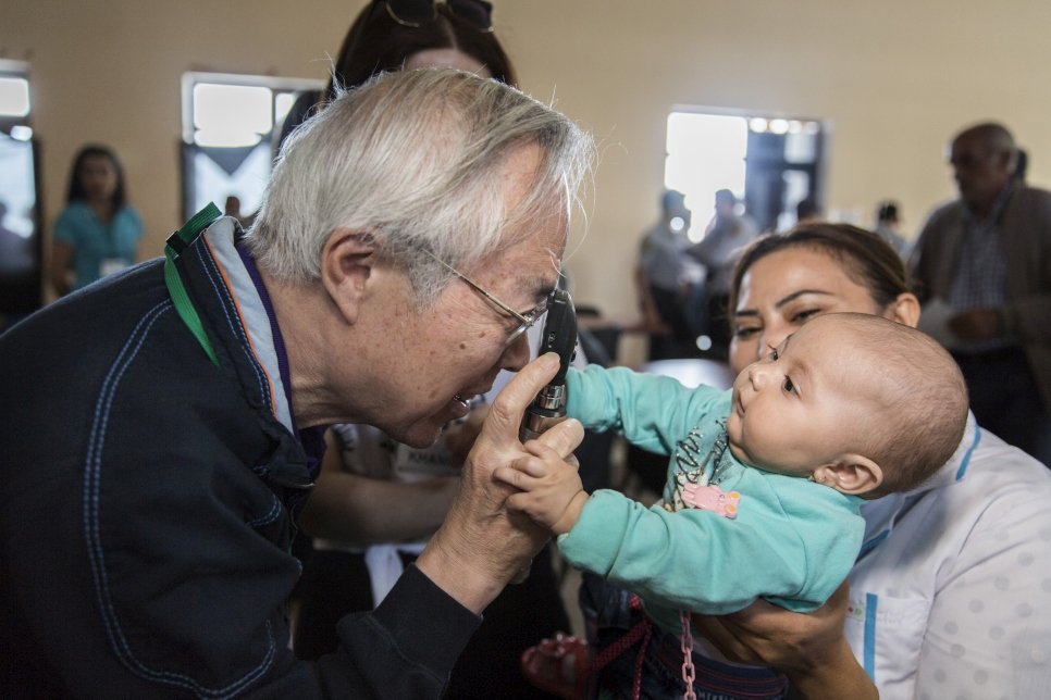 Dr Akio Kanai tries to examine an internally displaced infant's eyes.

During a six day eye-testing trip, the team screened 2,882 people and distributed 2,433 pairs of eyeglasses. in addition, 141 pairs of eyeglasses are to be sent from Japan.