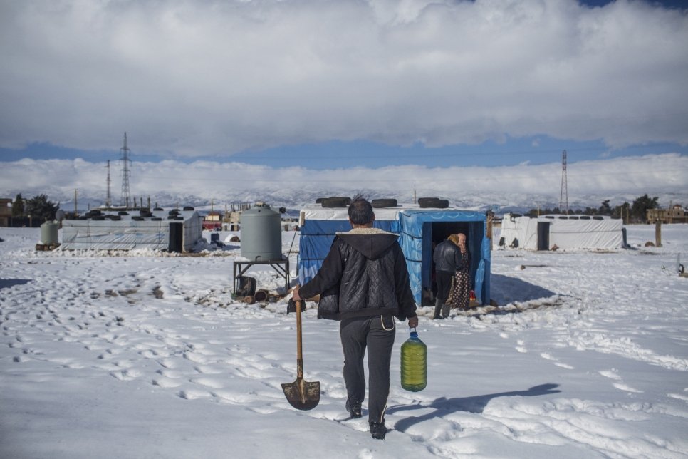 A Syrian refugee walks through the snow with a shovel and gasoline at the informal settlement camp of Douress. Lebanon is currently experiencing its harshest winter in years