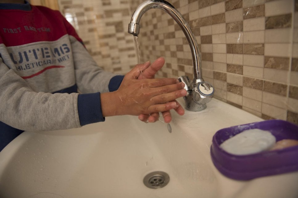 Jordan. Qusai (11) washes his hands in the sink at home